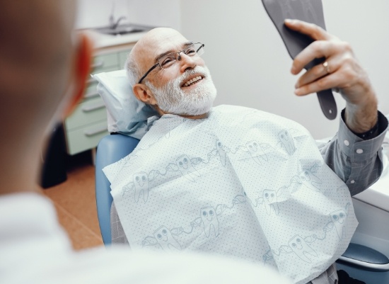 Man with dentures looking at smile in mirror