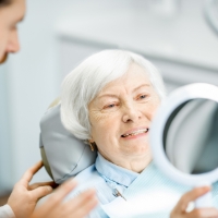 Woman looking at smile during initial dental implant consultation