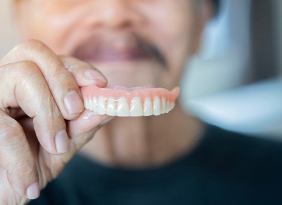 Man holding his denture