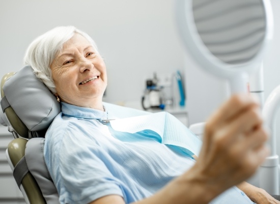 Woman with all on four dental implants looking in mirror