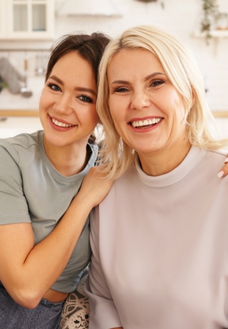 Two women sharing flawless smiles after cosmetic dental bonding