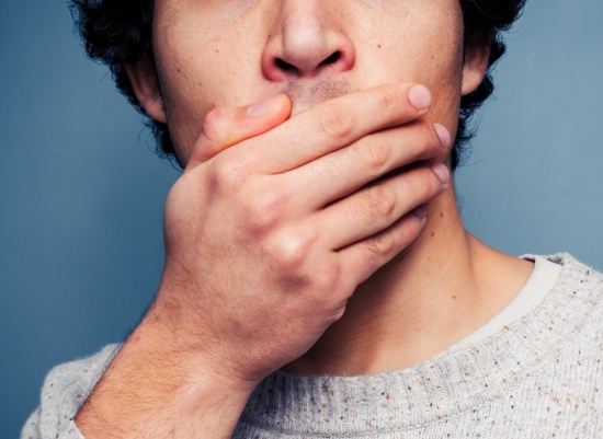 Man in need of cosmetic dental bonding covering his mouth