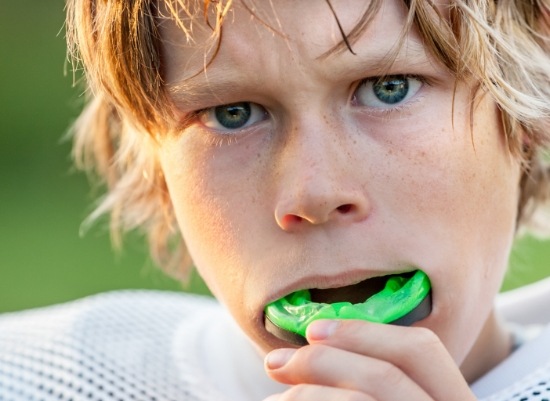 Teen placing a green athletic mouthguard