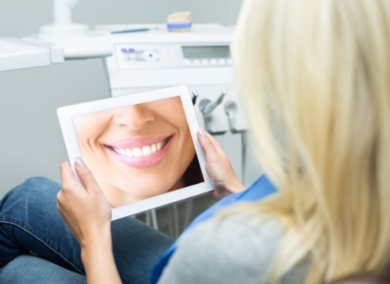 Woman looking at virtual smile design on tablet computer