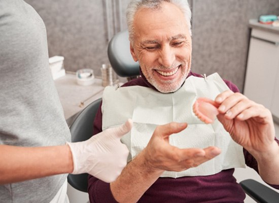 A dentist showing dentures to a patient