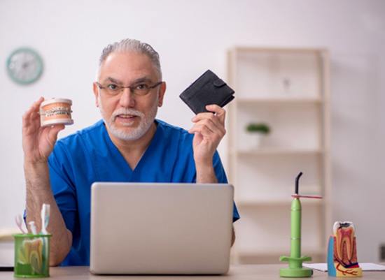 A dentist holding both a mock denture and a wallet