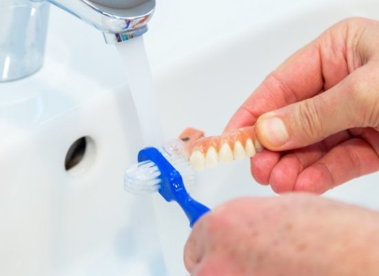 Person brushing their denture