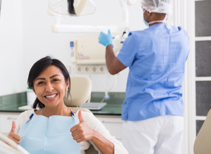 Woman in dental chair giving thumbs up