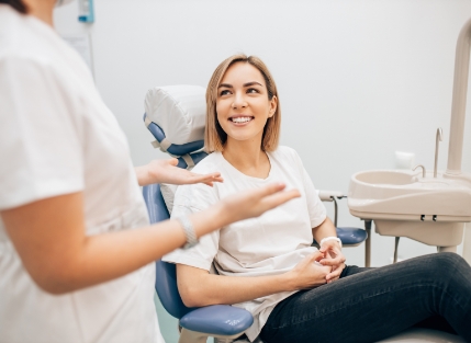 Woman in dental chair talking to dentist
