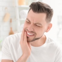 Man with jaw pain holding his cheek