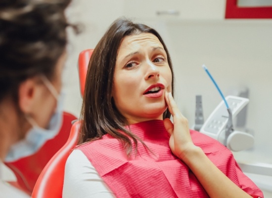 Woman in pain before emergency dentistry holding jaw in pain