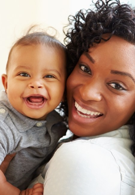 Mother holding smiling baby after frenectomy treatment