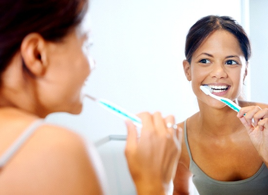 Woman brushing her dental implants in Houston with a toothbrush