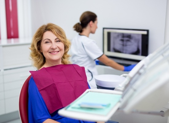 Woman smiling during dental implant supported dentures consultation