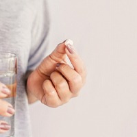 Woman taking a pill after getting dental implants in Houston