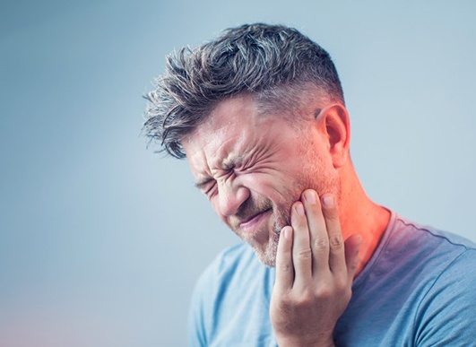 man holding the side of his face in pain 