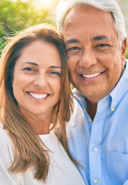 Man and woman smiling after tooth replacement with dental implants