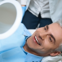 Man looking at smile after dental implant restoration