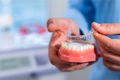 Dentist placing Invisalign aligners on model of teeth