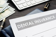 Dental insurance paperwork lying on desk with money