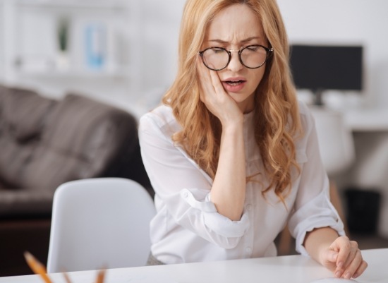 Woman in need of L P R F treatment holding jaw