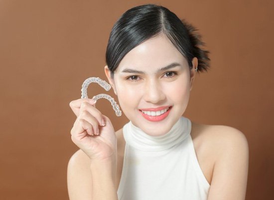 Lady smiles showing off Invisalign aligners