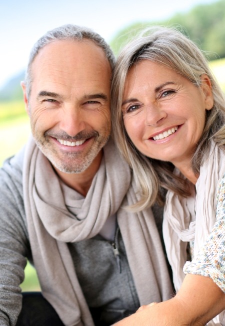 Man and woman smiling after replacing missing teeth