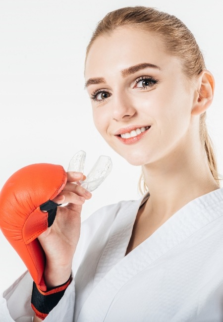 Teen girl with boxing gloves holding an athletic mouthguard