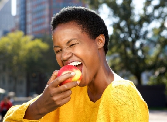 Woman eating an apple after dental crown and bridge treatment