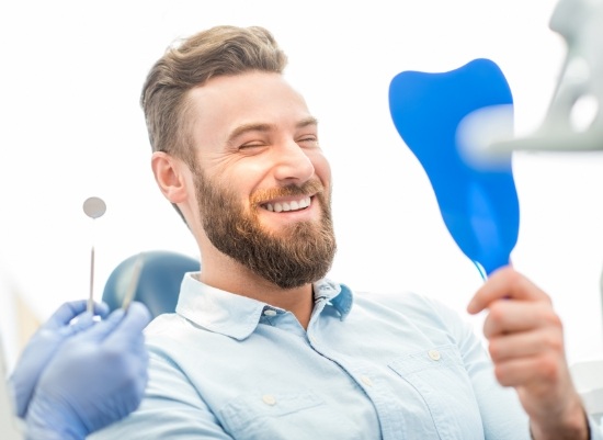 Man looking at smile after tooth colored filling and dental bonding treatment