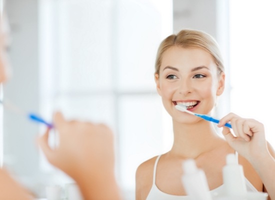 Woman brushing teeth after scaling and root planing