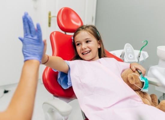Little girl giving dentist high five during children's dentistry visit