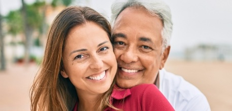 Man and woman smiling after replacing missing teeth