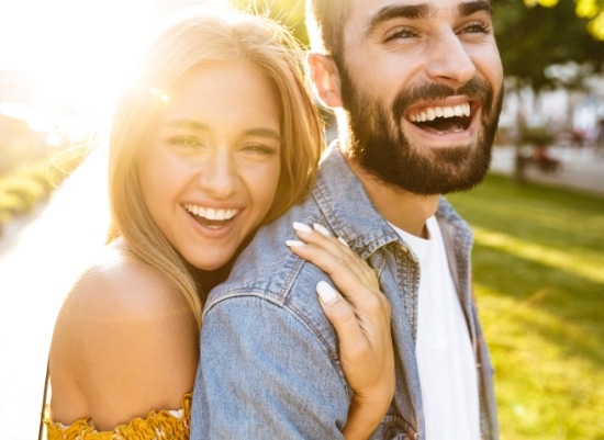 Man and woman sharing bright smiles after professional teeth whitening