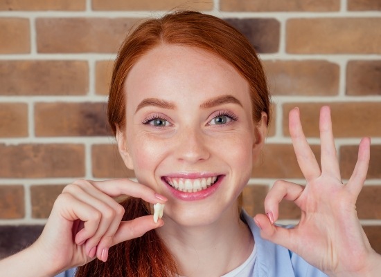 Woman holding up wisdom tooth after extraction