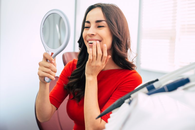 Woman smiling while feeling her dental implant
