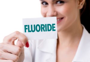 Woman showing benefits of fluoride on teeth.