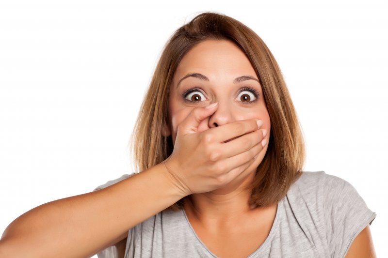 surprised woman with hand over her mouth
